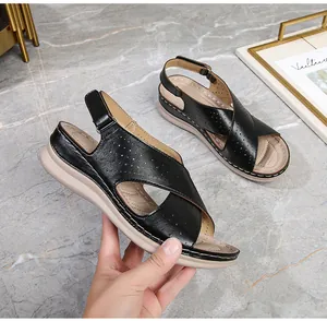 Close-up of black cross-strap platform sandals with perforated details and velcro closure