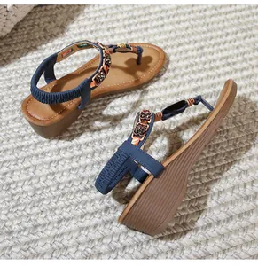 Detail view of Bohemian wedge sandals with flower embellishments and elastic blue heel strap