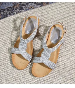 Détail de sandales compensées bohèmes argentées avec strass brillants et texture boisée