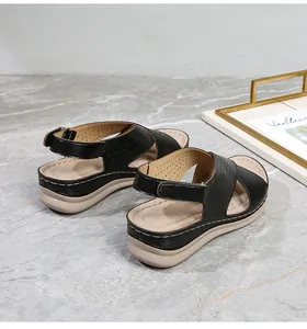 Detail of wedge sandals showing laser-cut strap patterns and velcro ankle strap