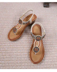 Dettaglio di sandalo zeppa boho con dischi di strass e cinturino elastico su stuoia