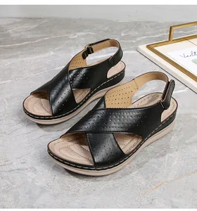 Close-up of black leather strap with laser-cut details on stylish platform wedge sandals