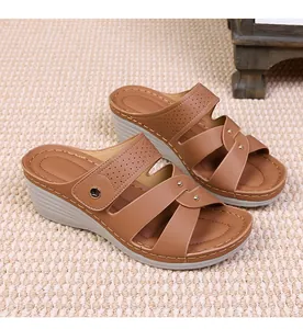 Detail view of brown wedge sandals featuring cutout patterns and golden metallic studs