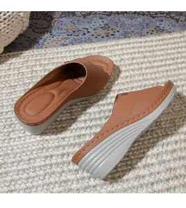 Detail of brown wedge sandals with wide straps and ergonomic footbed on straw mat