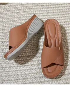Detail view of brown wedge sandal with criss-cross faux leather straps and metal stud