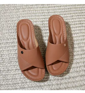 Detail of brown wedge slide sandals featuring crisscross straps and metal buckle accent