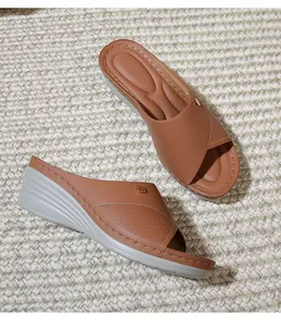 Detailed macro view of brown faux leather wedge sandals with laser-cut grid patterns