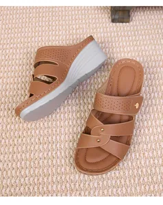 Detail of brown wedge sandals with laser-cut straps and decorative metallic studs