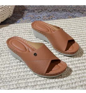 Detail of tan wedge sandals featuring hollow-out straps and wavy quilted footbed