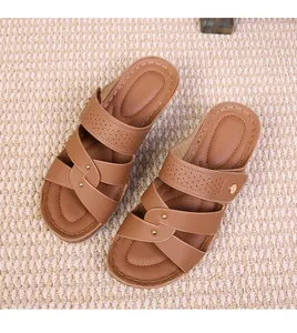 Detail of brown wedge slide sandals with crossover straps and gold rivets