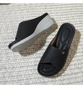 Side view of black wedge sandals with golden buckle and arch support on woven mat