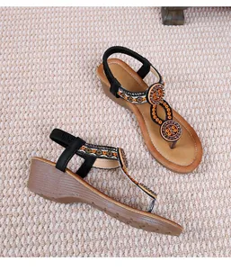 Dettaglio di sandali boho con zeppa caratterizzati da decorazioni di perline arancio e argento
