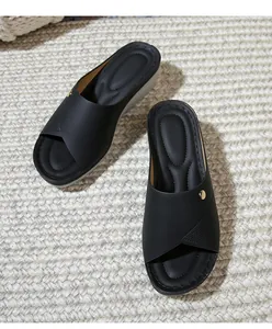 Detail of black wedge slides featuring a gold metal buckle and comfortable cushioned insole