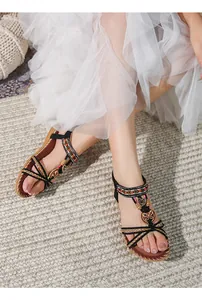 Dettaglio di sandali boho con perline colorate e ciondoli a farfalla in metallo vintage