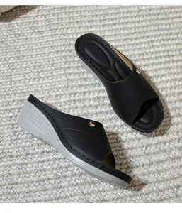 Detail of wedge slide sandals with textured peep toe upper and golden button accent