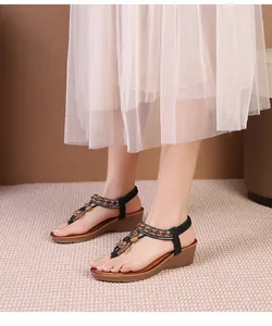 Ethnic bohemian wedge sandals with colorful beadwork and black straps on a model