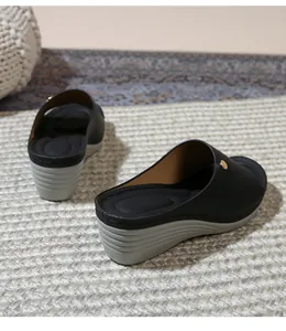 Detail view of women's wedge mule featuring a black upper and a stylish golden metal buckle