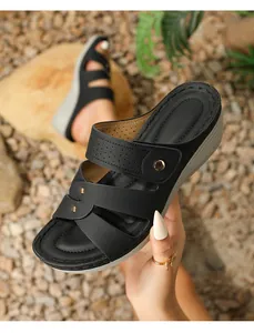 Detailed macro view of black wedge sandals with cross straps and gold stud accents