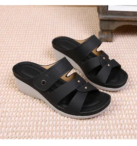 Detail view of black wedge sandals featuring decorative perforations and gold rivets