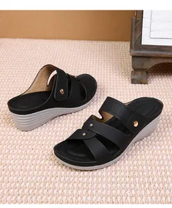 Detail of wedge sandals showing gold studs on black straps and breathable insoles
