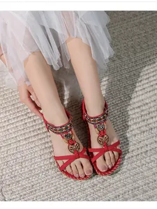 Dettaglio di sandali infradito rossi boho con ricami di perline e decori metallici