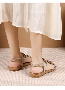 Detail van beige platte sandalen met glinsterende strassteentjes en bloemmotieven
