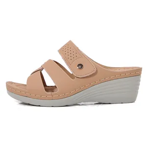 Women's beige wedge sandals with cross straps and decorative metal buckle on white background