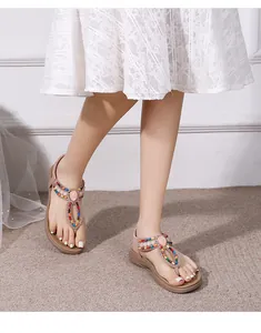 Close-up of bohemian flat sandals with colorful beads and gemstones on a woven rug