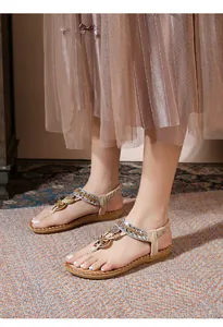 Detail of bohemian flat sandals with sparkling rhinestones and metal butterfly ornament