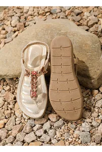 Detalle de sandalias planas doradas con mariposas de strass y suelas antideslizantes
