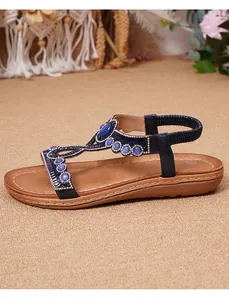 Détails de sandales plates bohèmes avec lanières bleues, strass et perles sur semelle brune