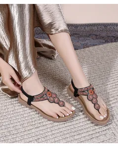Detail of bohemian T-strap flat sandals with floral discs and elastic back strap