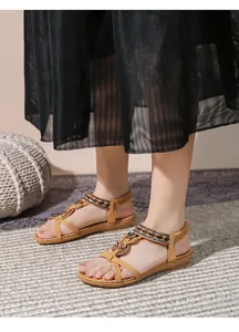 Dettaglio di sandali bohémien piatti con perline etniche e design a T in ecopelle gialla