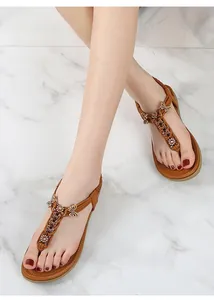 Detalle de sandalias con tira en T con mariposas de metal dorado y diamantes de imitación