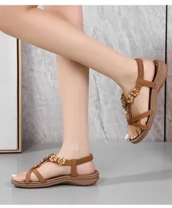 Détails de sandales plates bohèmes marron avec accents floraux et brides élastiques au talon