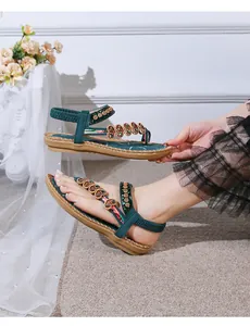 Close-up of bohemian green flat sandals with beaded heart charms and flexible backstrap