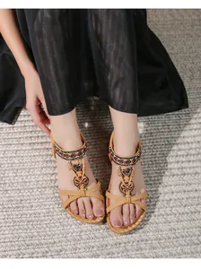 Dettagli di sandali boho con perline colorate, cuori in metallo e farfalle intrecciate