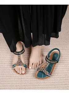 Detail van bohemien platte sandalen met groenblauwe bandjes en gekleurde kralen