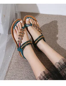 Detail of bohemian flat sandals with floral embroidery and heart crystal on dark green strap