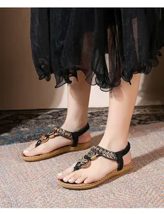 Detail of bohemian flat sandals with sparkling rhinestones and butterfly metal charms