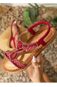 Détail de sandales bohèmes rouges avec strass et bride élastique au talon pour l'été