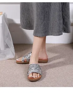 Close-up of women's silver braided flat sandals with metallic finish for summer wear