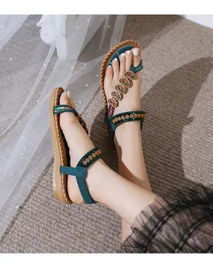 Close-up view of stylish bohemian flat thong sandals with star beads on model feet