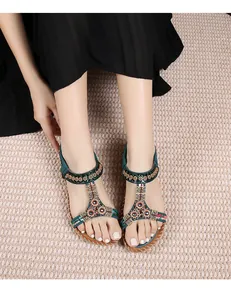 Detailopname van bohemien platte sandalen met kralen en groen voetbed op een modelvoet