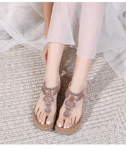 Detail of bohemian flat sandals with flower beadwork and thong straps in mauve