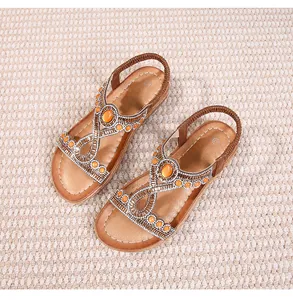 Détail de sandales plates bohèmes avec pierres oranges et strass brillants