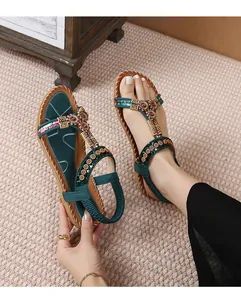 Detail van bohemian platte sandalen met groene zonnebloemaccenten en etnisch borduursel