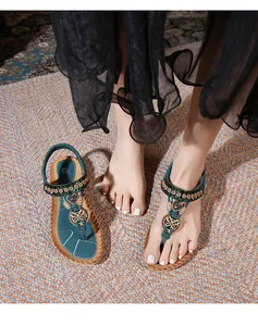 Detail of bohemian flat sandals with ethnic beads, metal butterfly, and heart charms