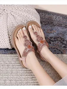 Detail of flat flip-flop sandals featuring rhinestone beading and floral T-strap design