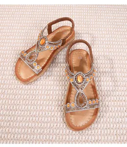 Détail de sandales plates bohèmes avec pierres oranges et strass scintillants